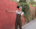 Art 85 - Femme-portant-des-lunettes-de-soleil-et-un-chignon-se-tenant-à-un-mur-rouge